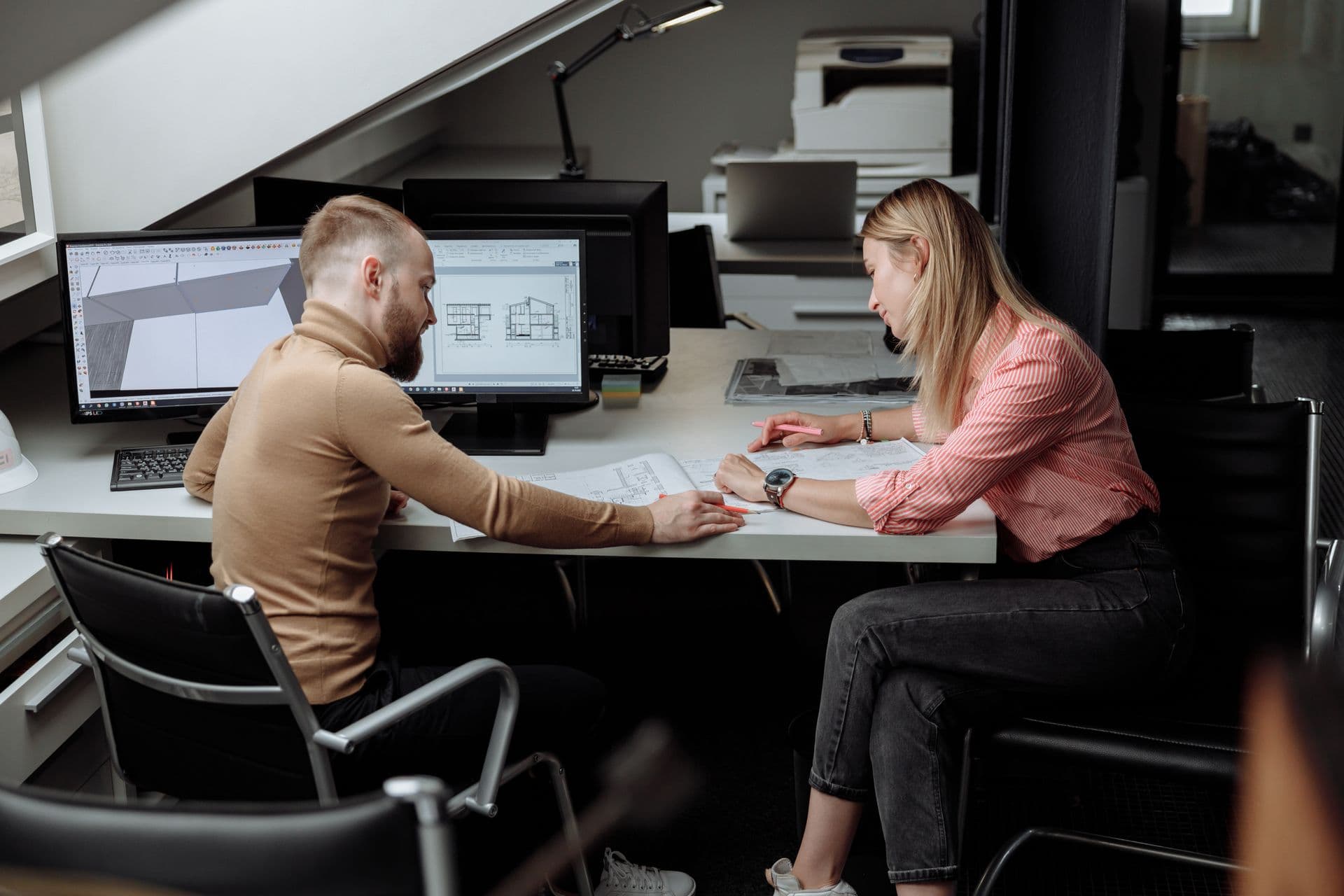 Two architects reviewing project plans together at a desk